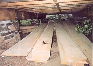 Crawl space under the cabin, showing the nine mortared stone piers and carry beams of tripled 2 x 12's.